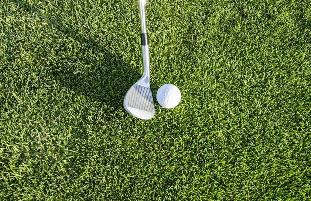 Golfová hůl a míček na trávě, ilustrační fotografie